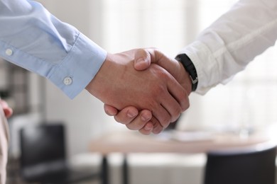 Photo of Men shaking hands in agreement indoors, closeup