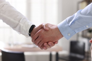 Photo of Men shaking hands in agreement indoors, closeup