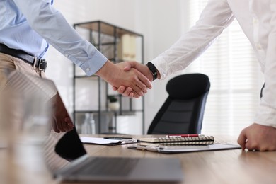 Photo of Men shaking hands at table in office, closeup