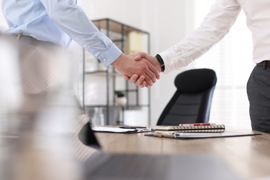 Photo of Men shaking hands at table in office, closeup