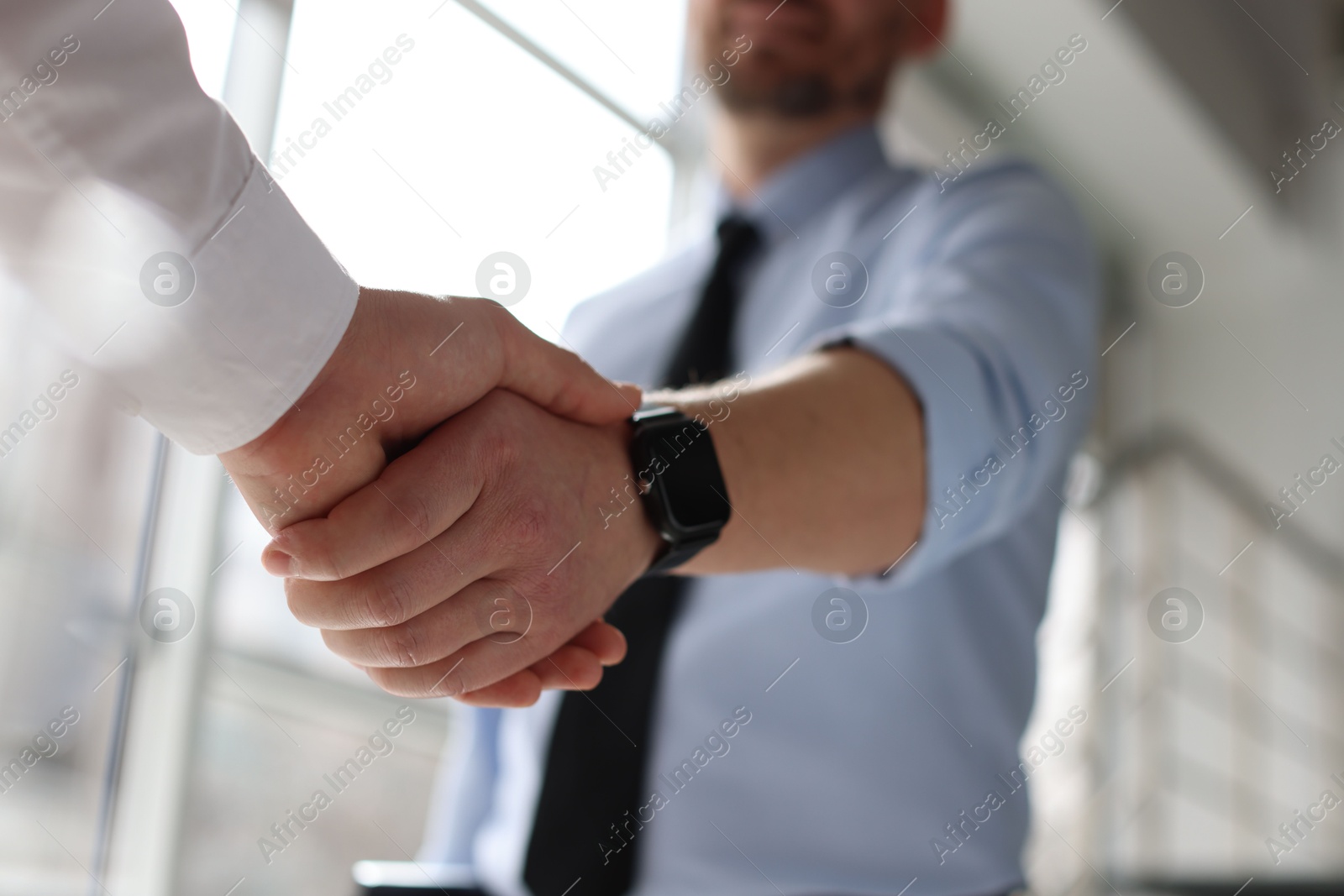 Photo of Men shaking hands in agreement indoors, closeup