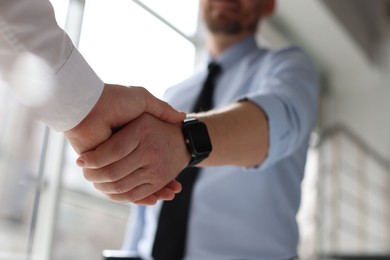 Men shaking hands in agreement indoors, closeup