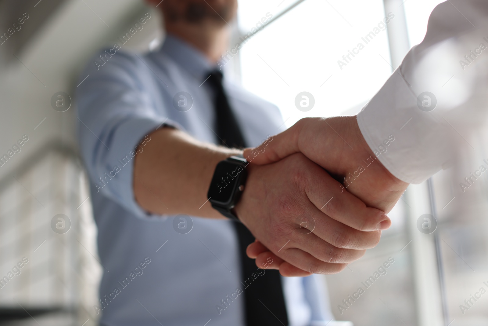 Photo of Men shaking hands in agreement indoors, closeup