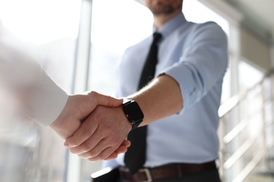 Photo of Men shaking hands in agreement indoors, closeup