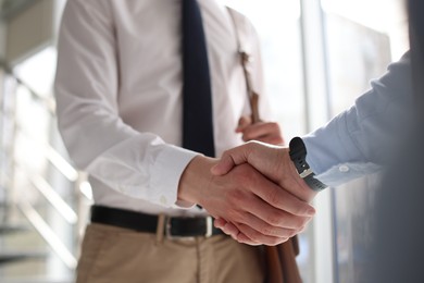 Photo of Men shaking hands in agreement indoors, closeup