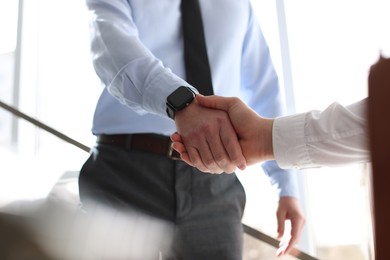 Photo of Men shaking hands in agreement indoors, closeup