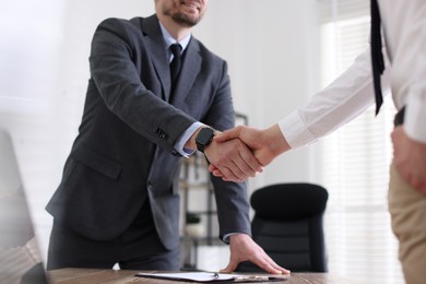 Men shaking hands at table in office, closeup