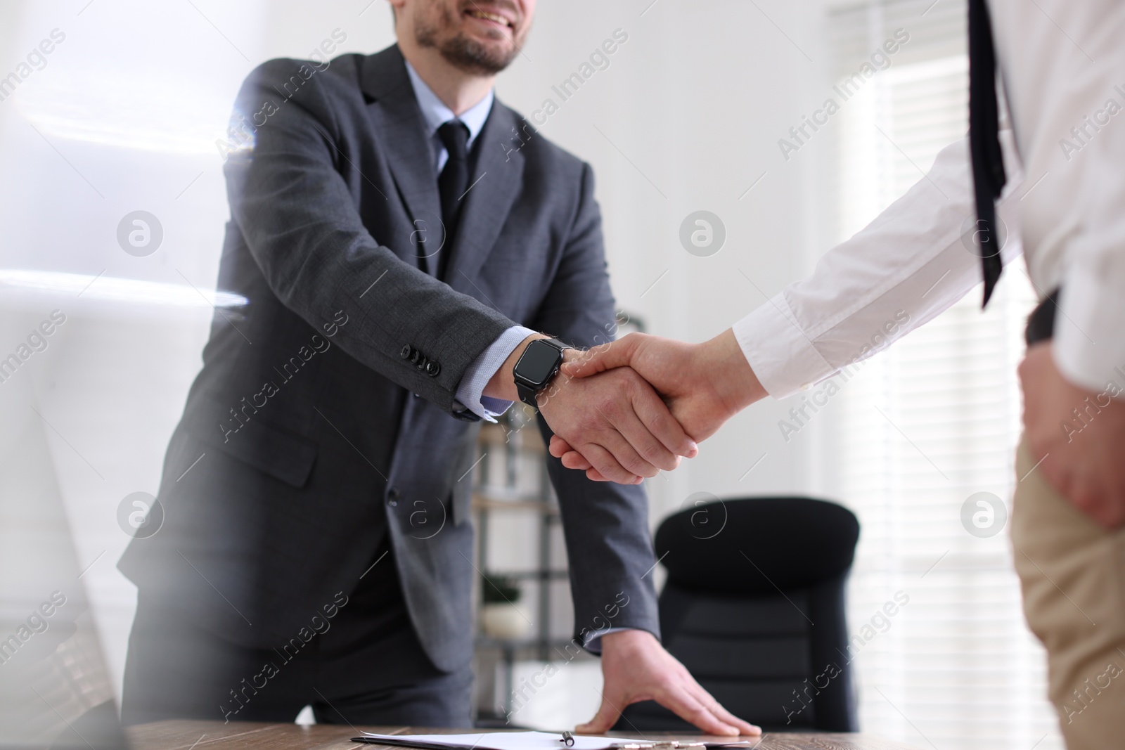 Photo of Men shaking hands at table in office, closeup