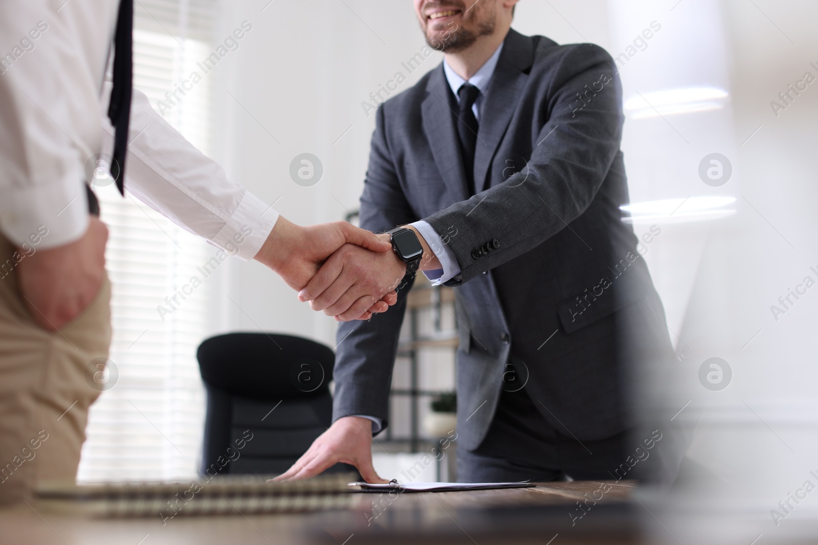 Photo of Men shaking hands at table in office, closeup