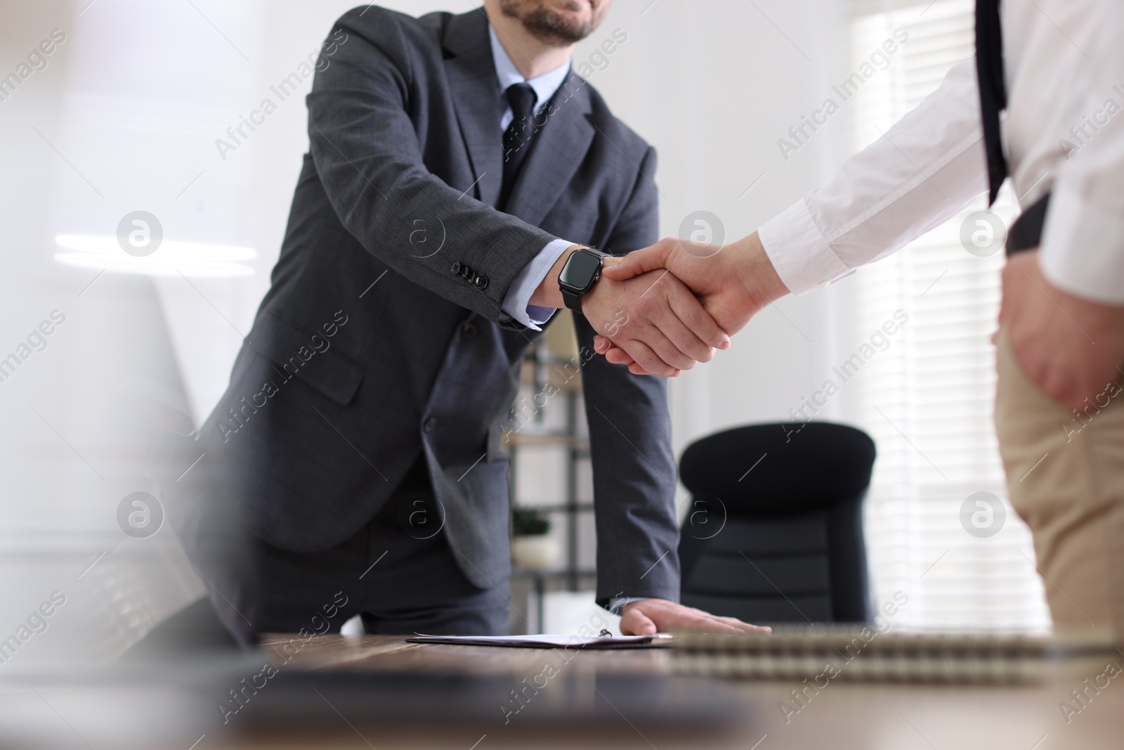 Photo of Men shaking hands at table in office, closeup