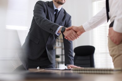 Photo of Men shaking hands at table in office, closeup