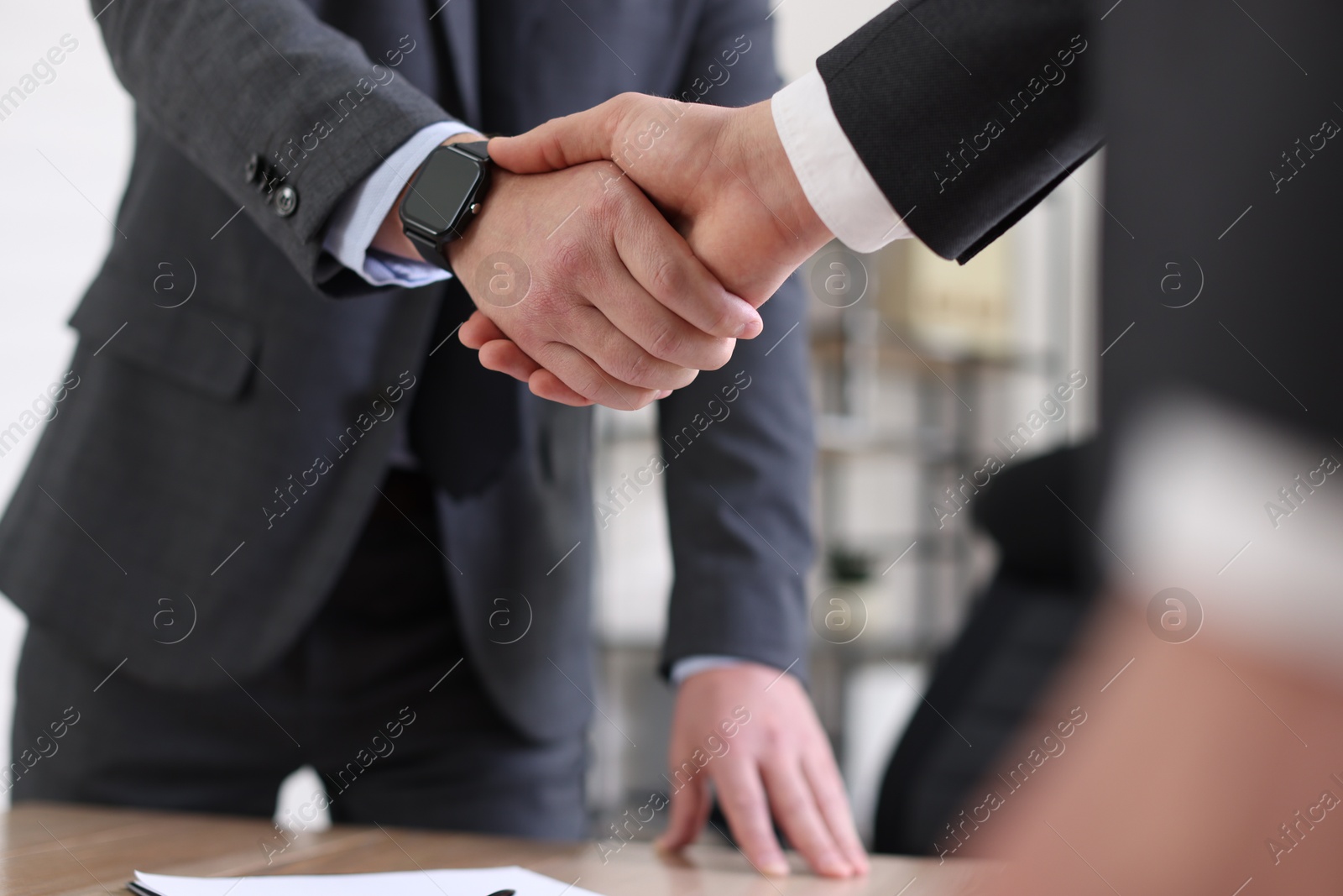 Photo of Men shaking hands during meeting in office, closeup