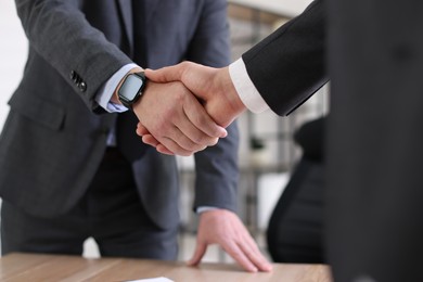 Photo of Men shaking hands during meeting in office, closeup