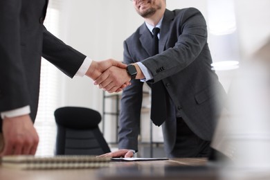 Photo of Men shaking hands at table in office, closeup