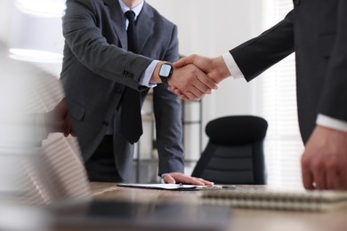 Photo of Men shaking hands at table in office, closeup