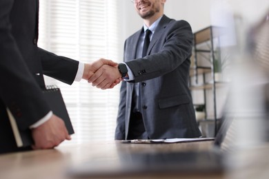 Men shaking hands at table in office, closeup