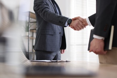 Photo of Men shaking hands during meeting in office, closeup