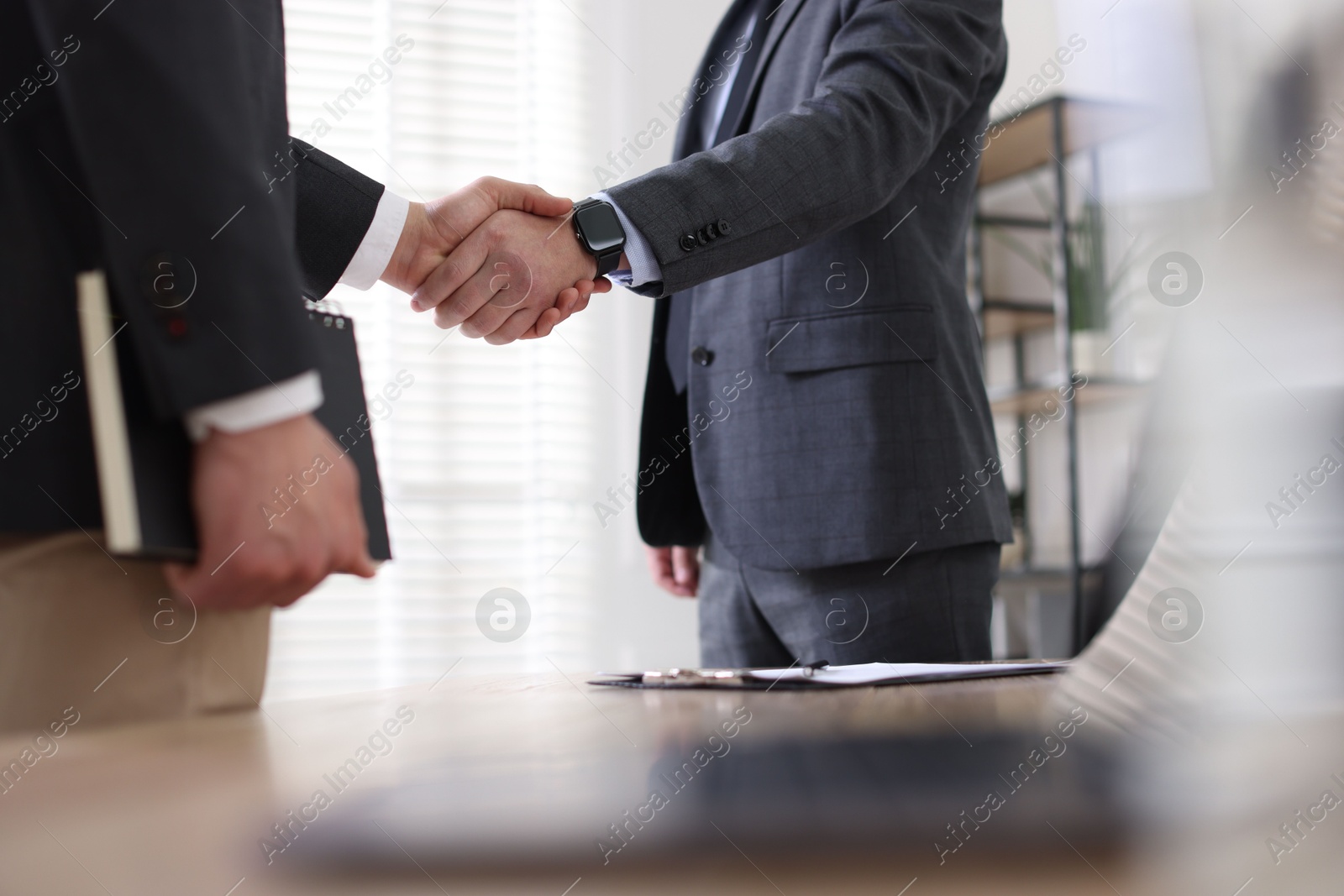 Photo of Men shaking hands during meeting in office, closeup