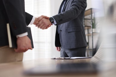 Photo of Men shaking hands during meeting in office, closeup