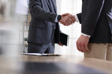 Photo of Men shaking hands during meeting in office, closeup