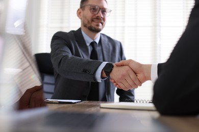 Men shaking hands at table in office, selective focus