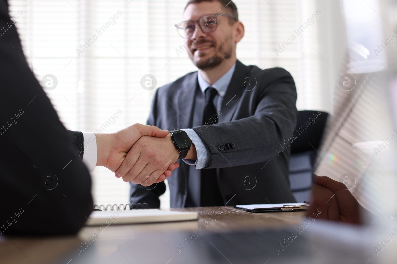 Photo of Men shaking hands at table in office, selective focus