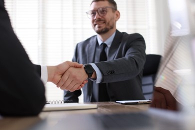 Photo of Men shaking hands at table in office, selective focus