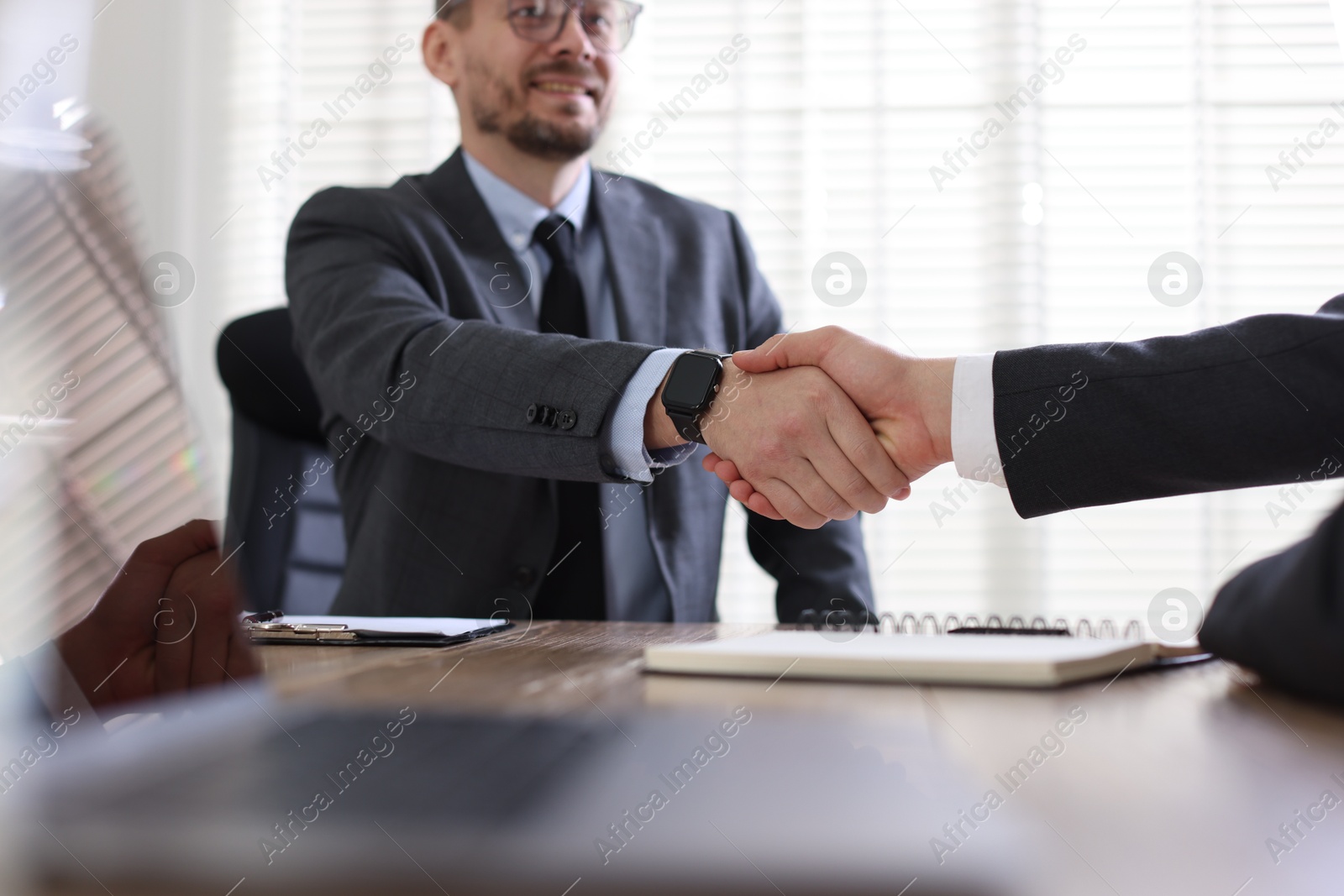 Photo of Men shaking hands at table in office, selective focus