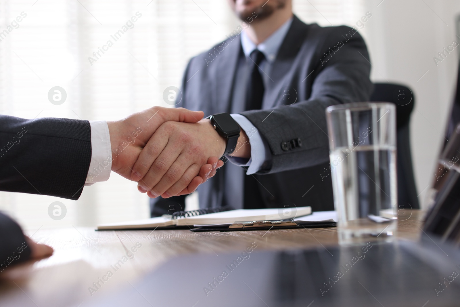 Photo of Men shaking hands at table in office, closeup