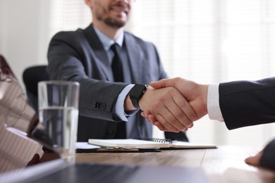 Photo of Men shaking hands at table in office, closeup