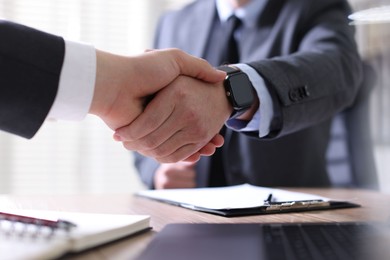 Photo of Men shaking hands at table in office, closeup