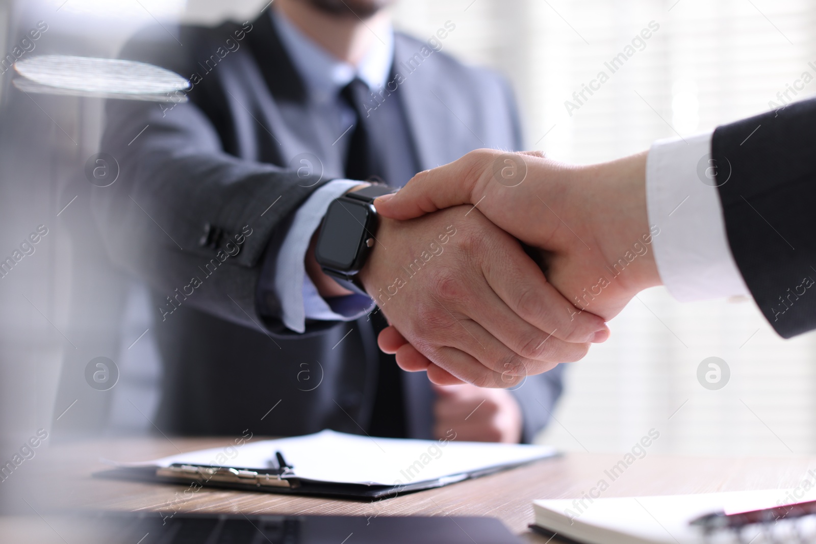 Photo of Men shaking hands at table in office, closeup