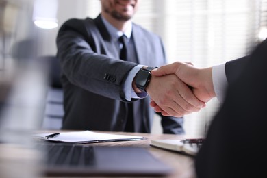 Photo of Men shaking hands at table in office, closeup