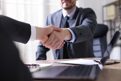 Photo of Men shaking hands at table in office, closeup