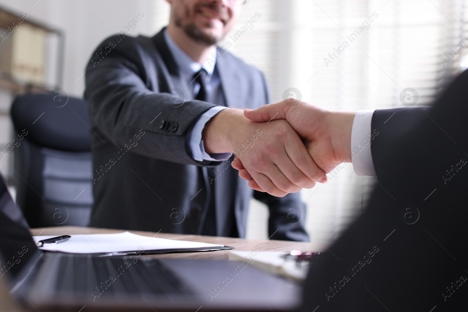 Photo of Men shaking hands at table in office, closeup