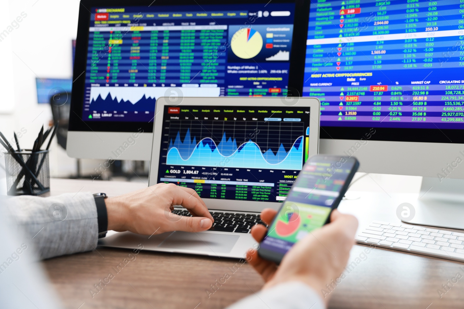 Photo of Financial trading specialist with smartphone and laptop at table in office, closeup