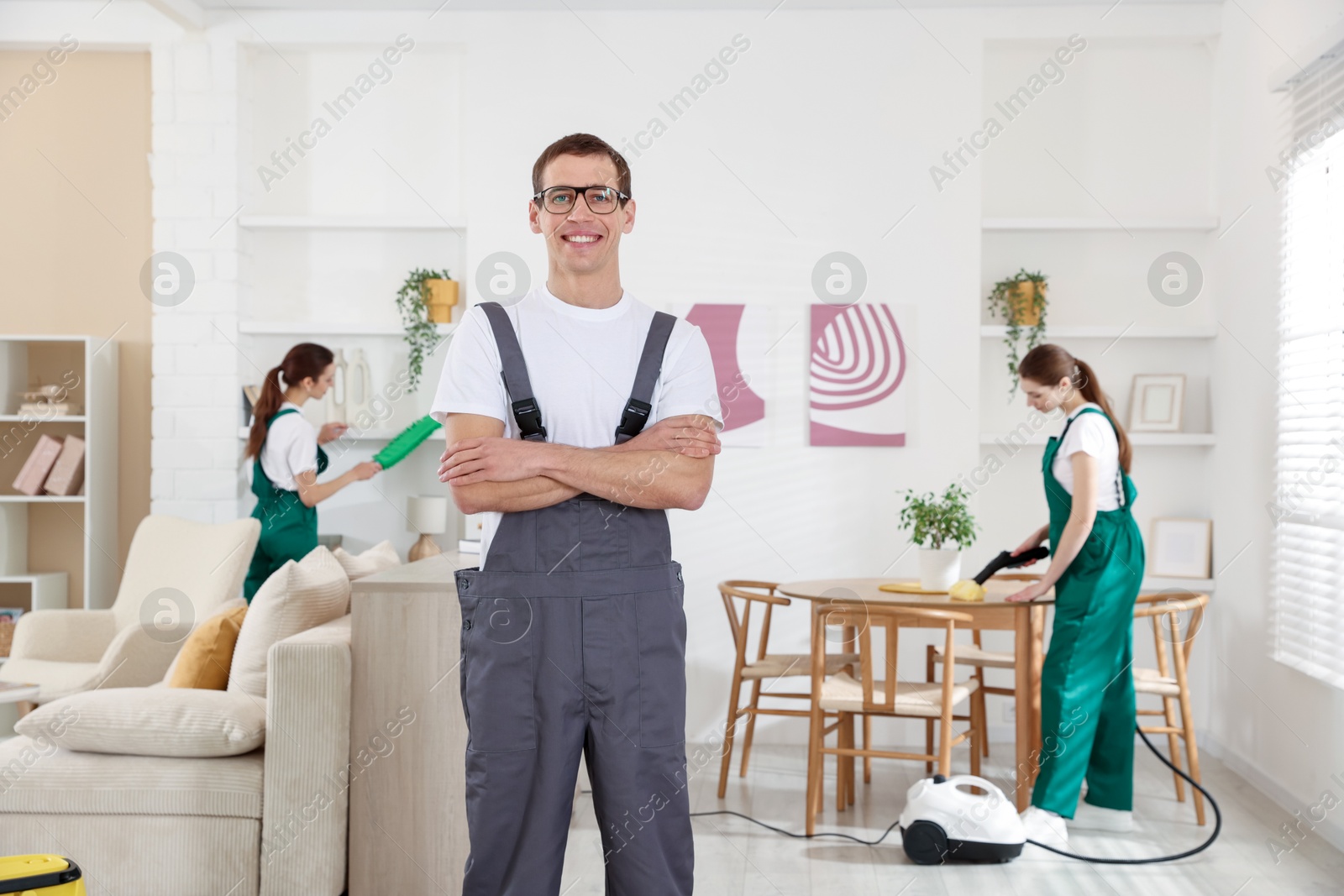 Photo of Professional cleaning service team working in room