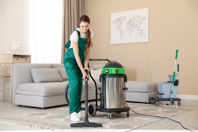 Professional cleaning service worker vacuuming rug indoors