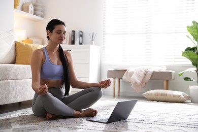 Photo of Woman with laptop meditating on floor at home. Space for text