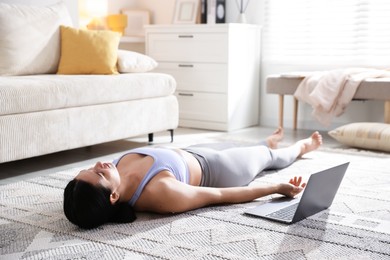 Photo of Woman with laptop meditating on floor at home