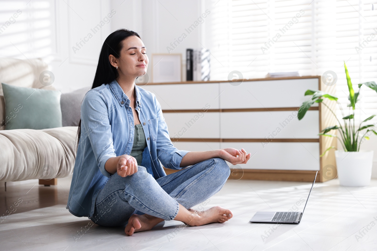 Photo of Woman with laptop meditating on floor at home. Space for text