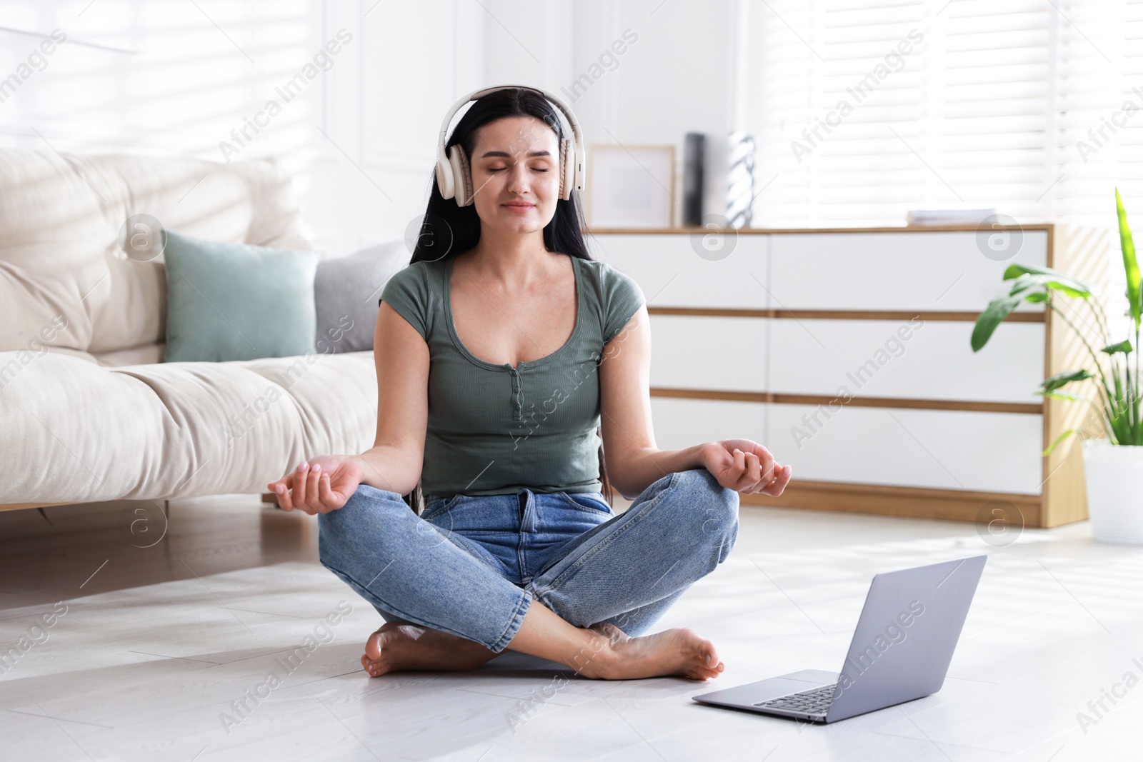 Photo of Woman with laptop meditating on floor at home