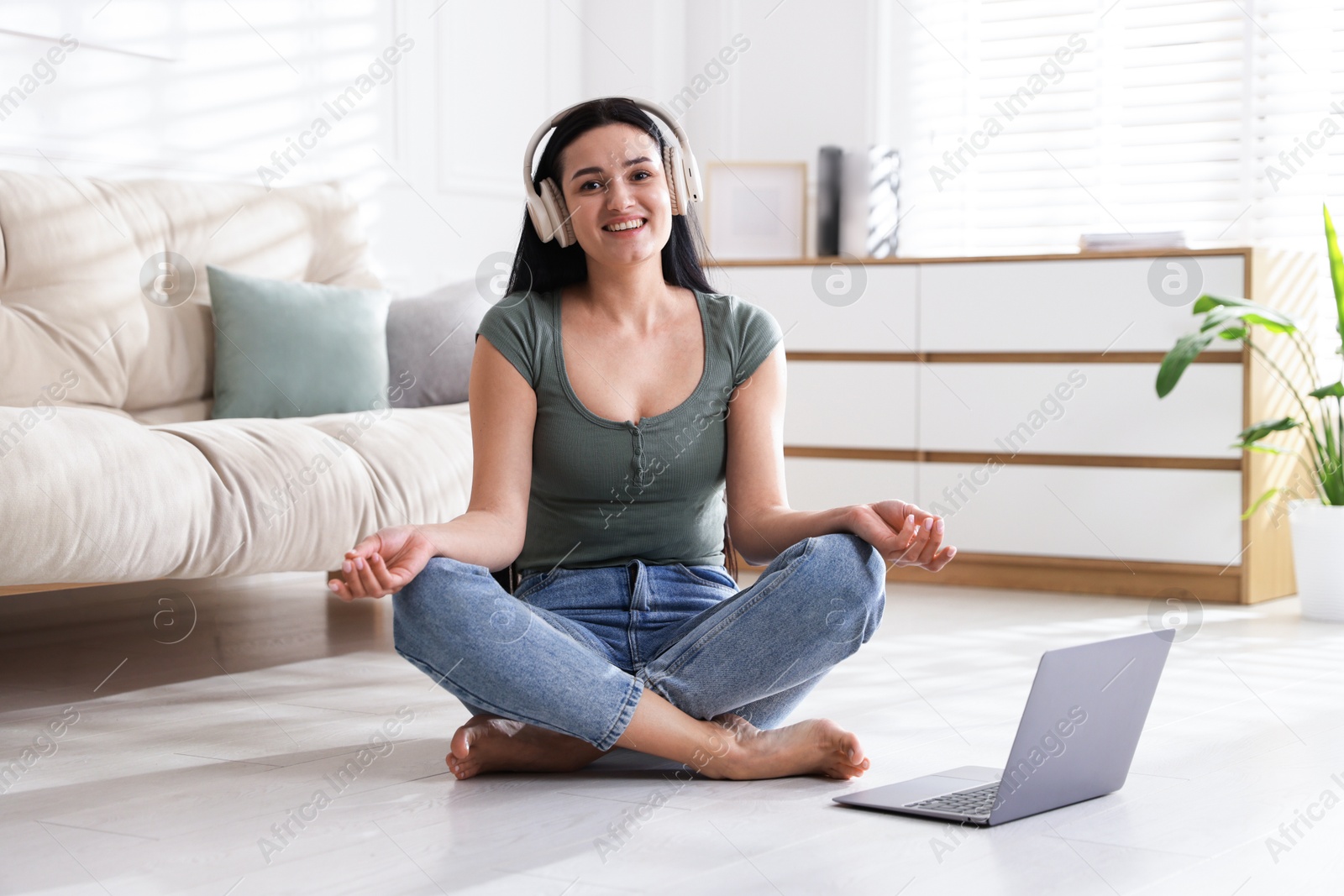 Photo of Woman with laptop meditating on floor at home