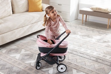 Cute little girl with doll stroller at home