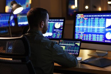 Financial trading specialist working in office at night, back view