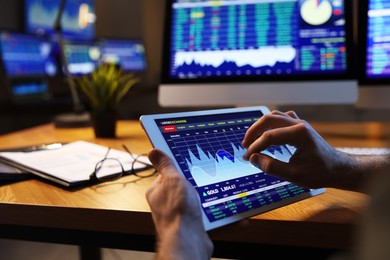 Photo of Financial trading specialist with tablet in office at night, closeup