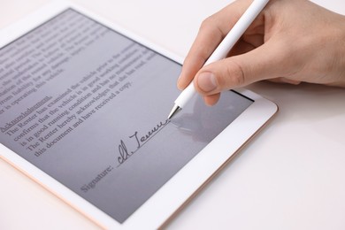 Photo of Electronic signature. Man using stylus and tablet at white table, closeup