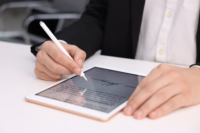 Photo of Electronic signature. Man using stylus and tablet at white table, closeup