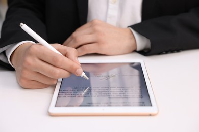 Photo of Electronic signature. Man using stylus and tablet at white table, closeup