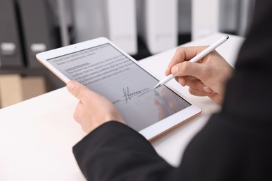 Photo of Electronic signature. Man using stylus and tablet at white table, closeup